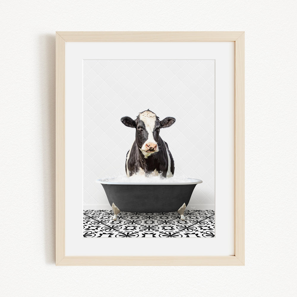 A black and white cow is sitting in a black bathtub filled with water, creating a whimsical and playful scene.