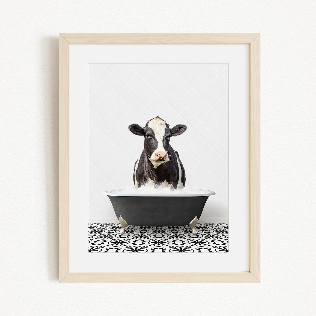 A black and white cow is sitting in a black bathtub filled with water, creating a whimsical and playful scene.