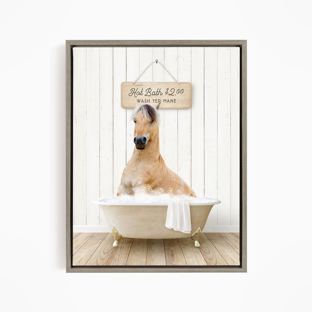 A light brown horse is sitting in a white bathtub filled with water, with a wooden sign above it that reads "Hot Bath $2.00 WASH YE MANE".