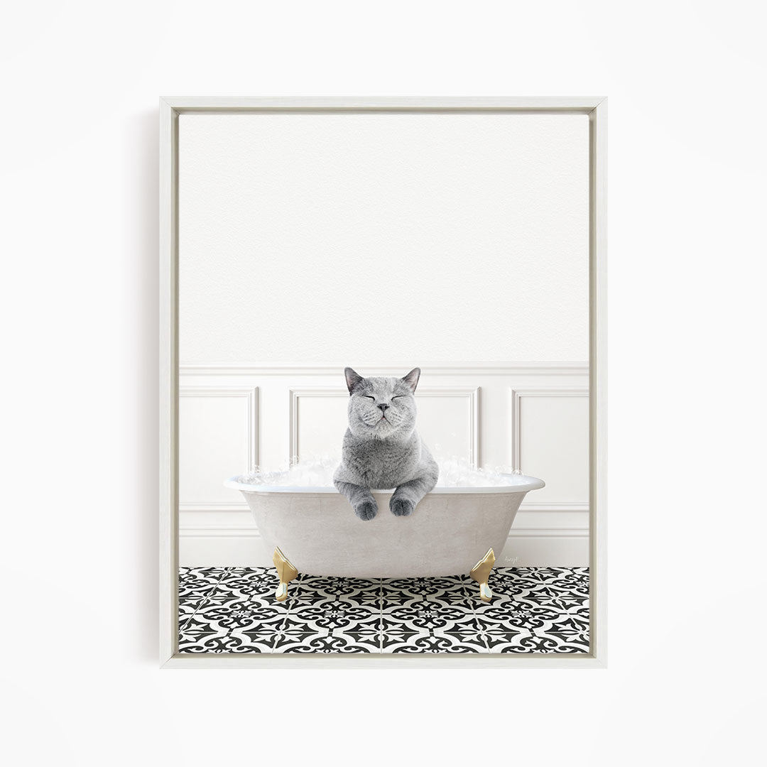 A gray cat sitting in a white bathtub filled with bubbles, with a black and white patterned floor in the background.
