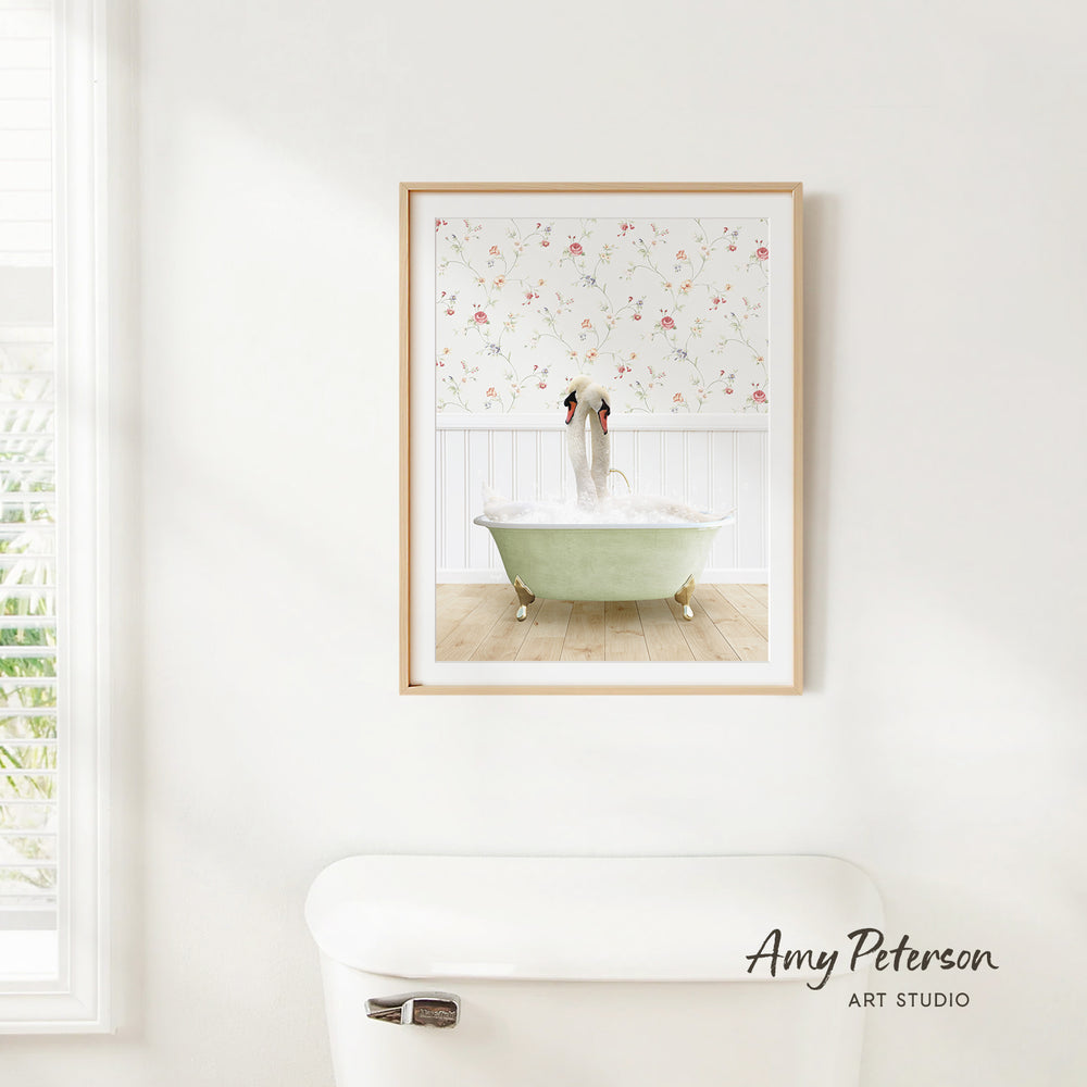A framed image of a green clawfoot bathtub filled with water, with a floral pattern on the wall behind it, is hanging on a white wall in a bathroom.