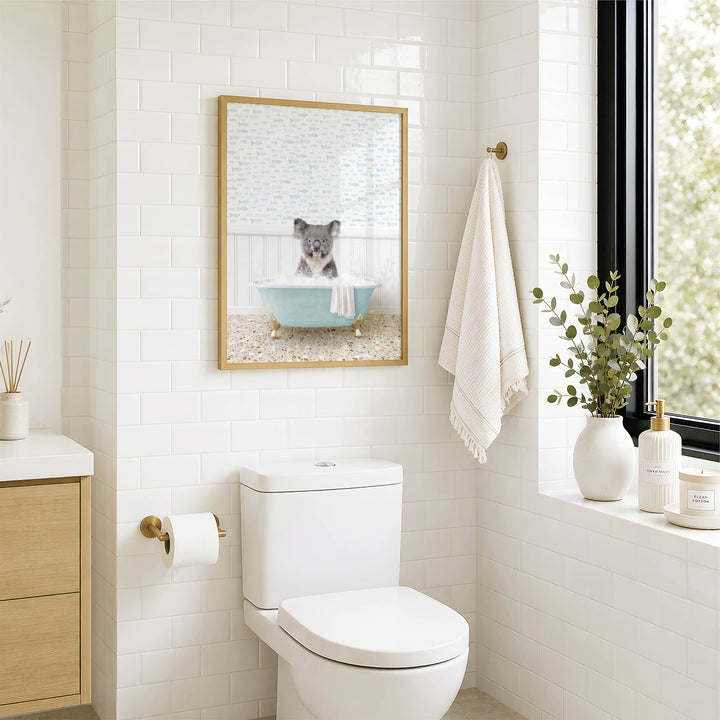A bathroom with a white toilet, a framed picture of a koala sitting in a bathtub, and a towel hanging on the wall.