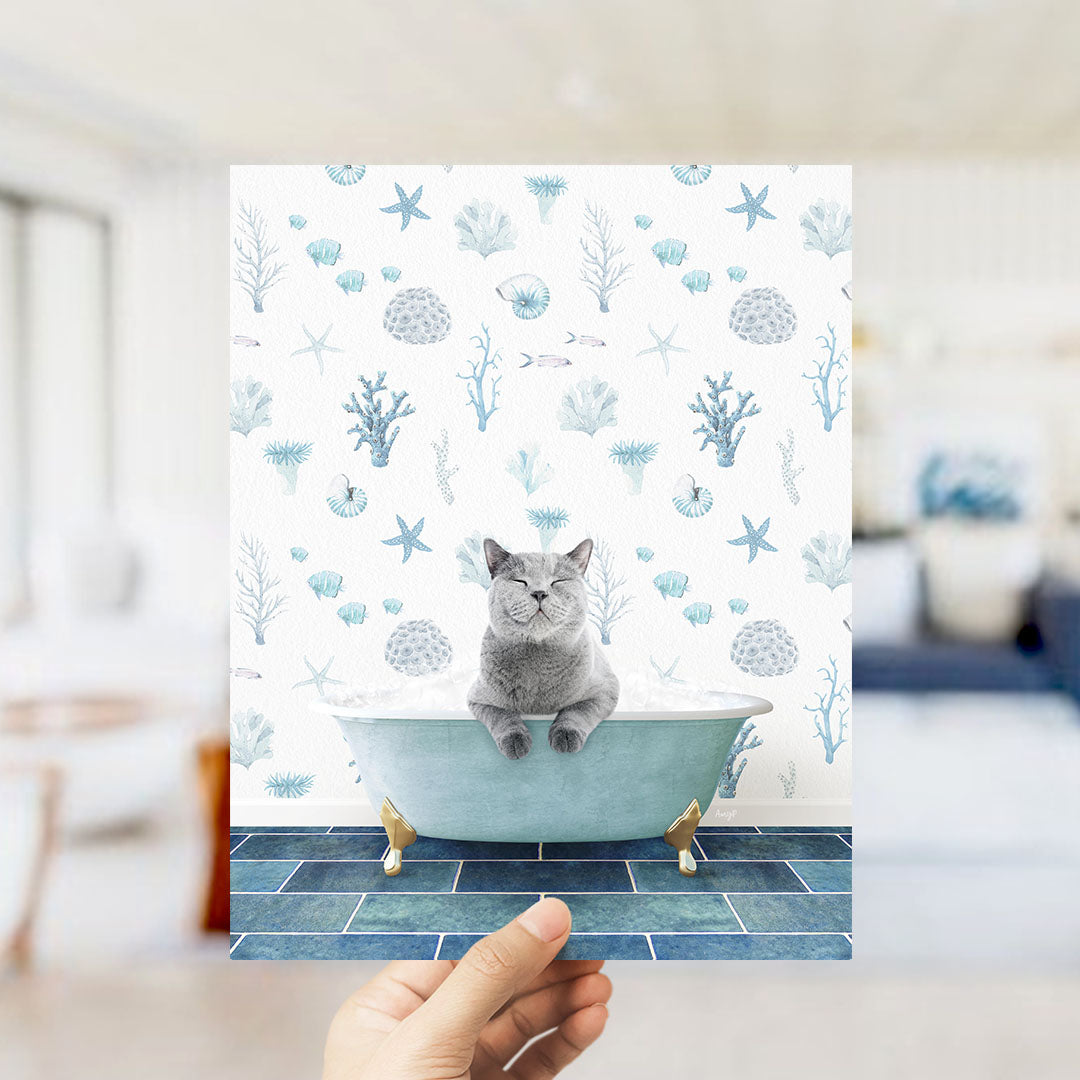 A gray cat sitting in a blue bathtub filled with bubbles, surrounded by a pattern of seashells, starfish, and other marine life.