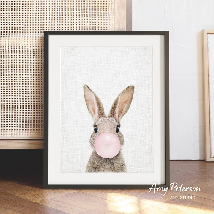 A framed image of a rabbit blowing a bubble with a pink bubblegum bubble.