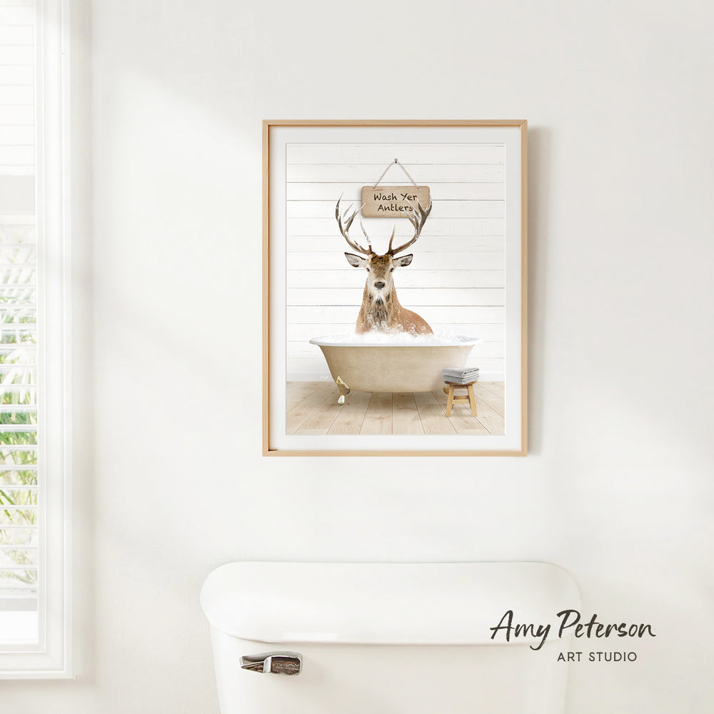 A framed image of a deer sitting in a bathtub, with a sign above it that says "Witch Your Antlers".
