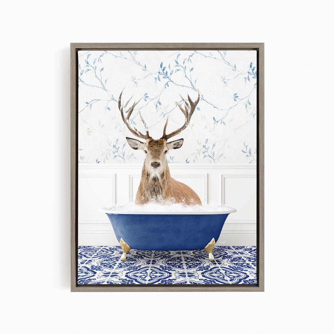 A deer with large antlers is sitting in a blue bathtub, surrounded by a patterned tile floor and a floral wallpaper background.