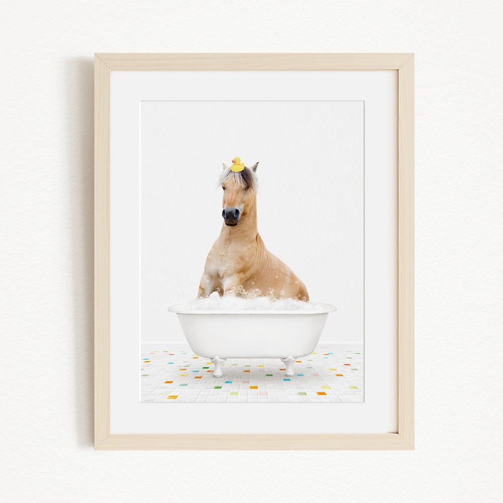 A horse is sitting in a white bathtub filled with bubbles, with a rubber duck perched on its head.
