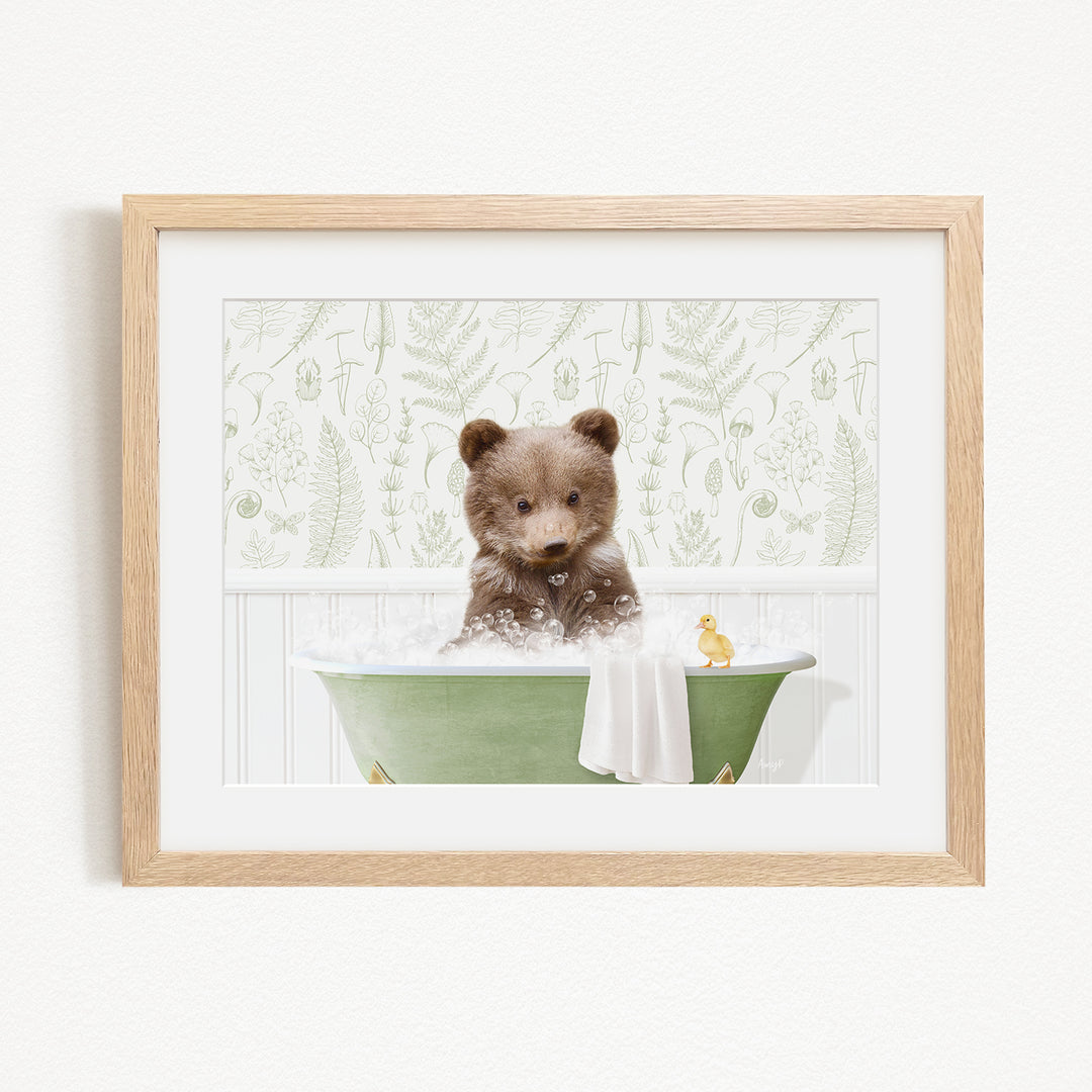 A cute brown bear cub sitting in a green bathtub filled with bubbles, with a yellow rubber duck floating nearby.