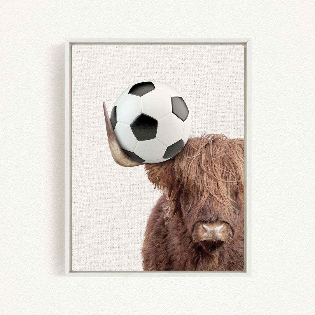 A brown cow with long hair is holding a soccer ball in its head.