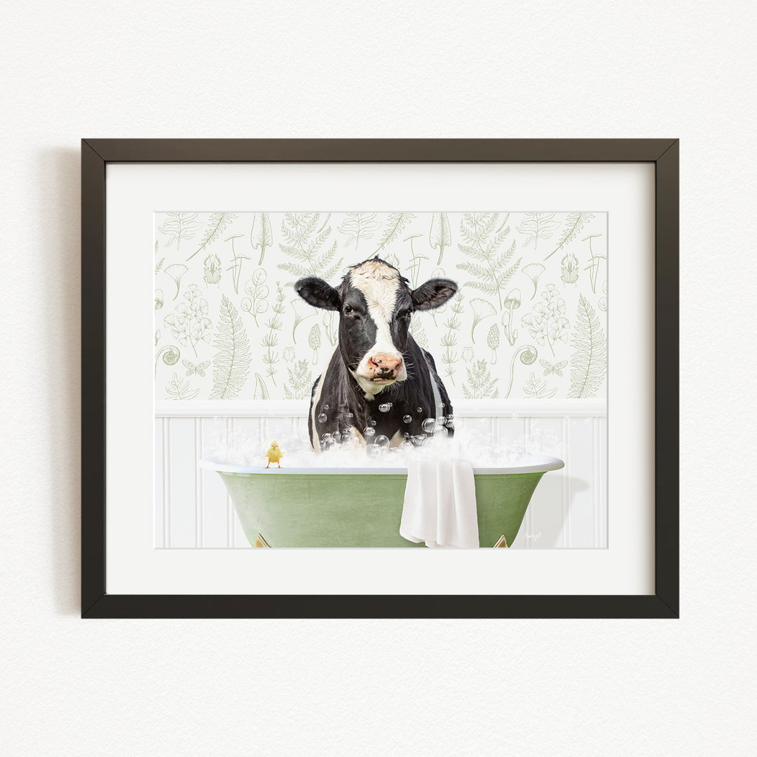 A black and white cow is sitting in a green bathtub filled with bubbles, with a yellow bird perched on the edge of the tub.