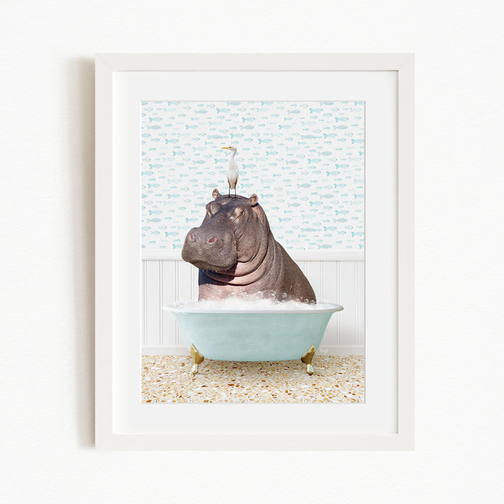A framed image depicting a hippopotamus sitting in a bathtub, with a bird perched on its head.