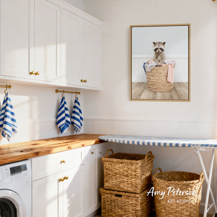 A laundry room with white cabinets, a wooden countertop, and a framed picture of a raccoon sitting in a basket.