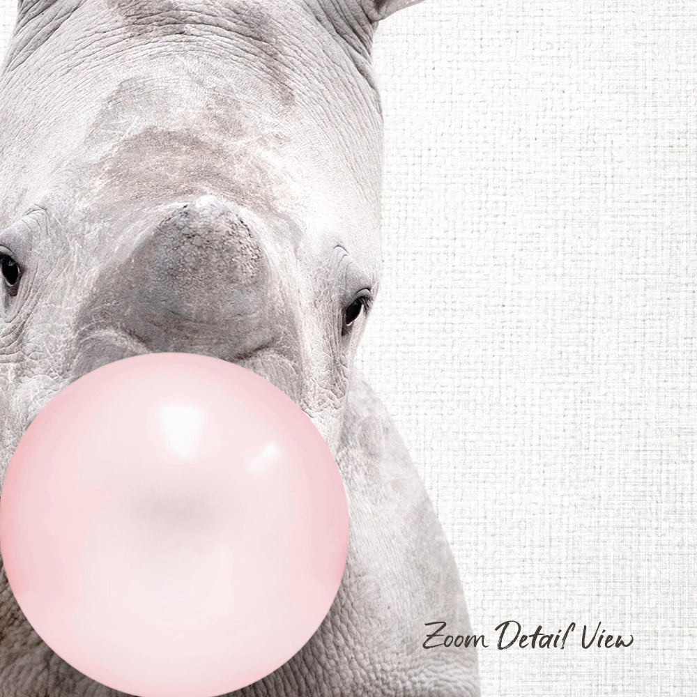 A close-up of a rhinoceros blowing a pink bubble with its mouth, against a plain white background.