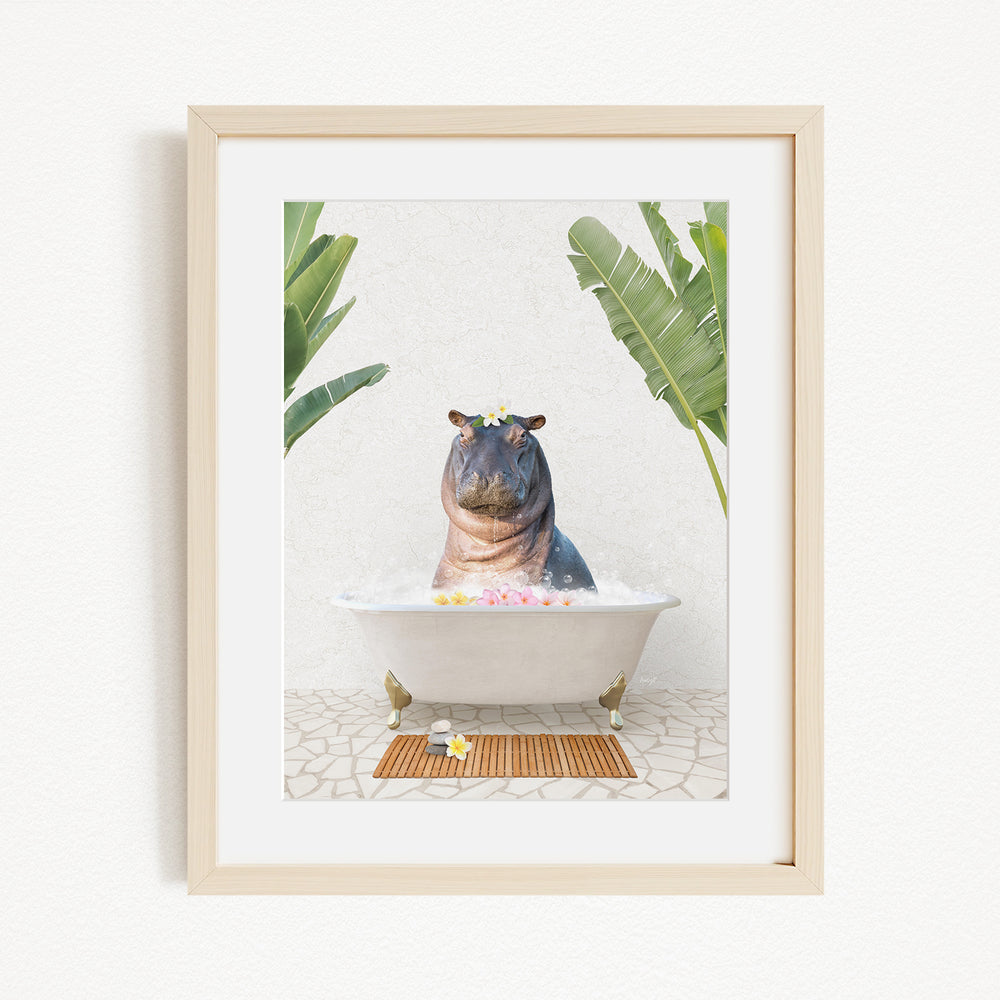 A framed image depicting a hippopotamus sitting in a bathtub filled with bubbles, surrounded by tropical plants.