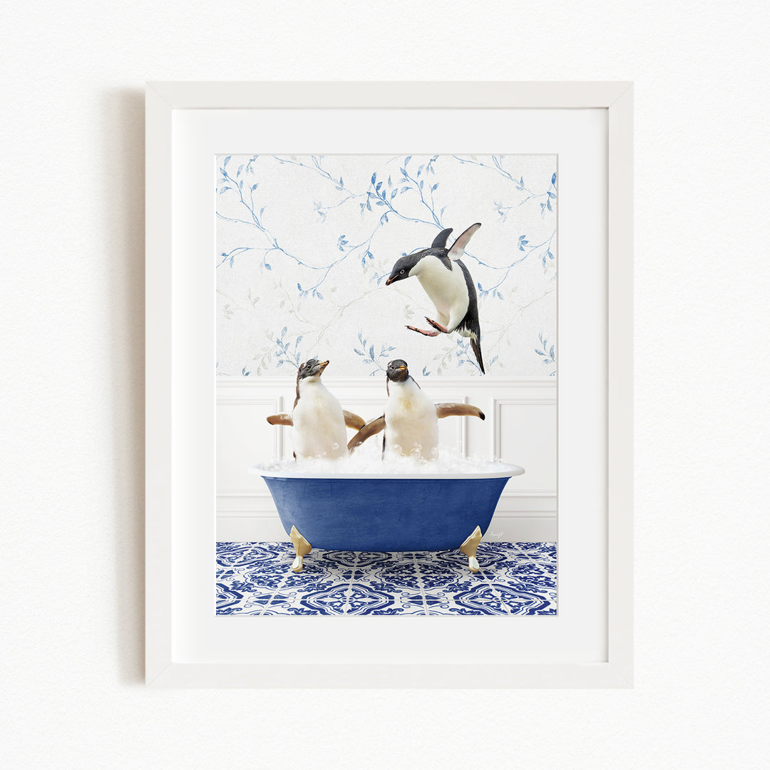 A framed image depicting two penguins sitting in a blue bathtub, with one penguin jumping out of the tub.