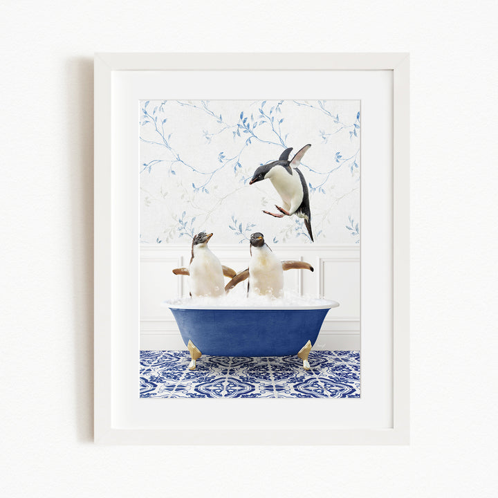 A framed image depicting two penguins sitting in a blue bathtub, with one penguin jumping out of the tub.
