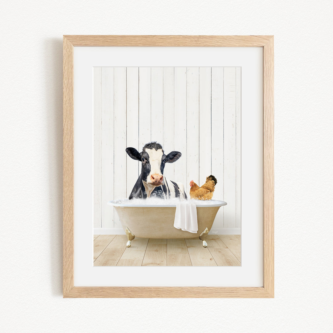 A black and white cow is sitting in a bathtub filled with water, with a chicken nearby, in a wooden frame.