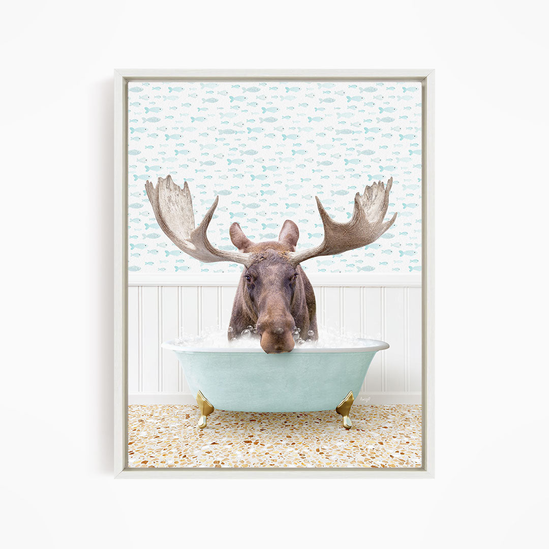 A moose with large antlers is sitting in a light blue bathtub filled with water, surrounded by a pattern of small fish.