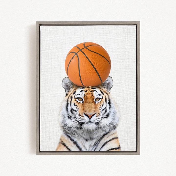 A tiger is sitting on a basketball, with the basketball positioned on its head.