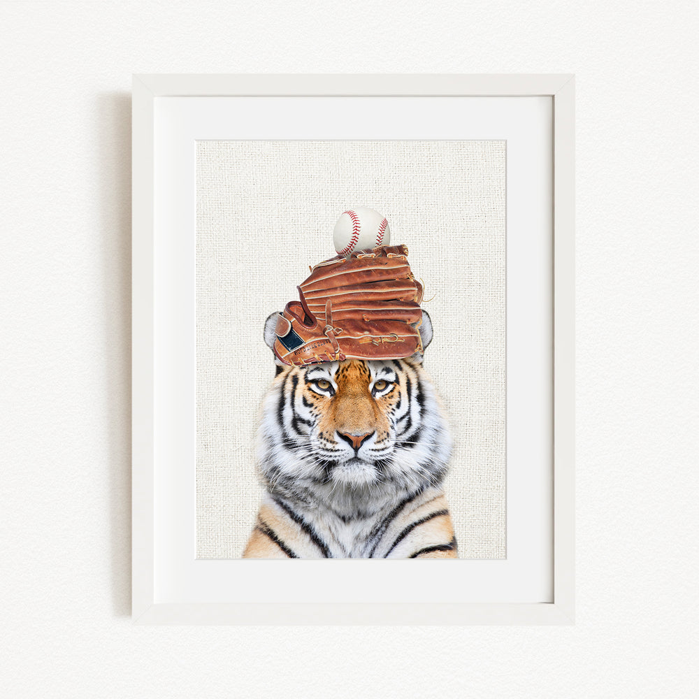 A tiger wearing a baseball cap and holding a baseball glove in its mouth.