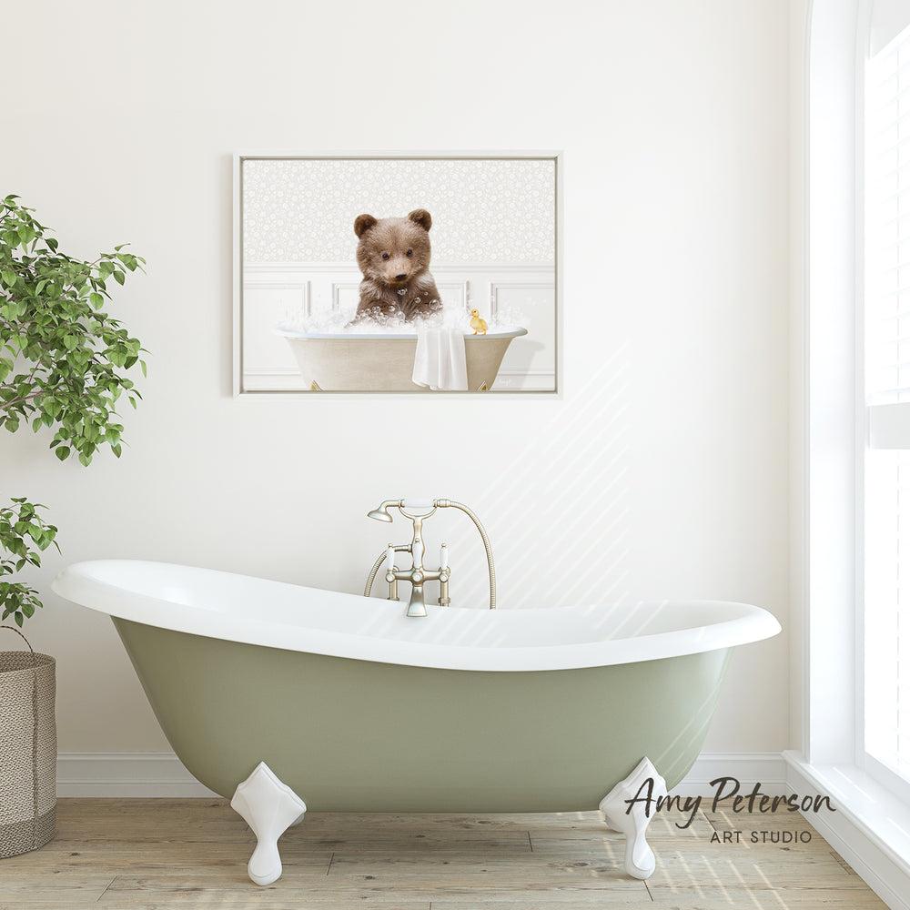 A framed image of a bear sitting in a bathtub is displayed on the wall above a green clawfoot bathtub in a bathroom.