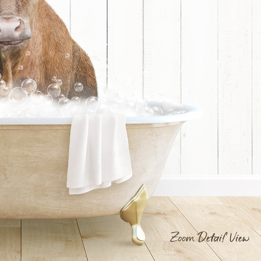A brown cow is sitting in a bathtub filled with bubbles, with a towel and gold bathtub leg visible.