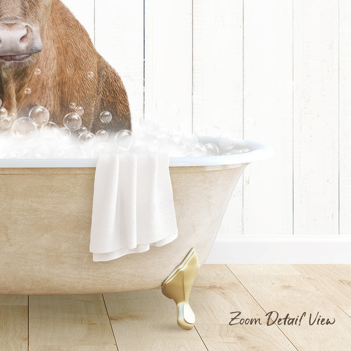 A brown cow is sitting in a bathtub filled with bubbles, with a towel and gold bathtub leg visible.