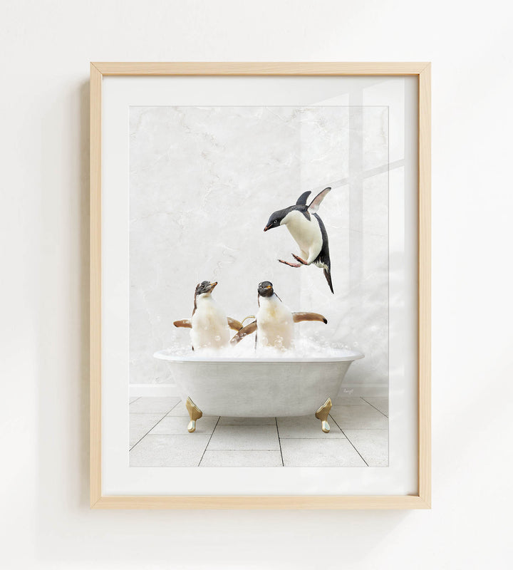 A framed image depicting two penguins sitting in a bathtub, with one penguin standing on the edge of the tub and another penguin sitting inside the tub.