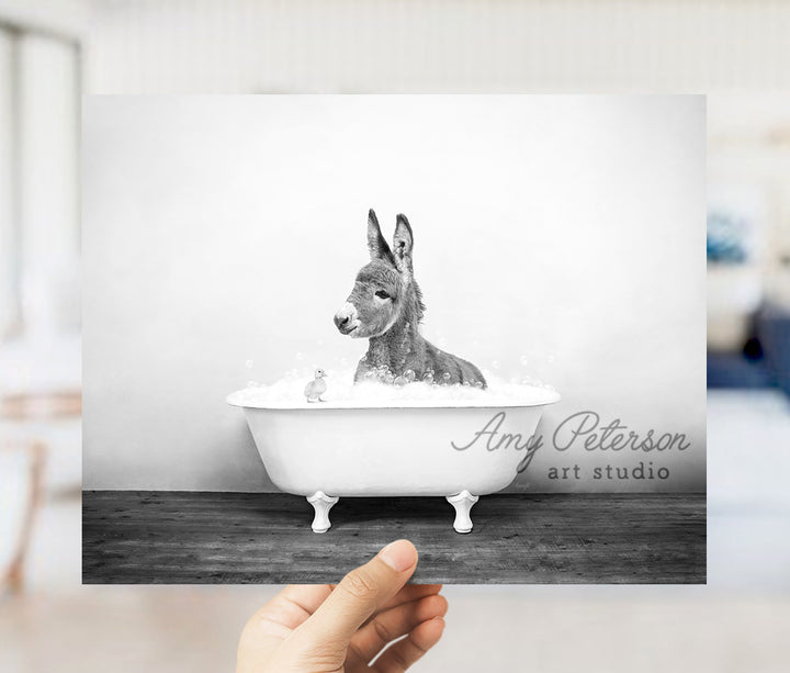 a person holding up a picture of a donkey in a bathtub