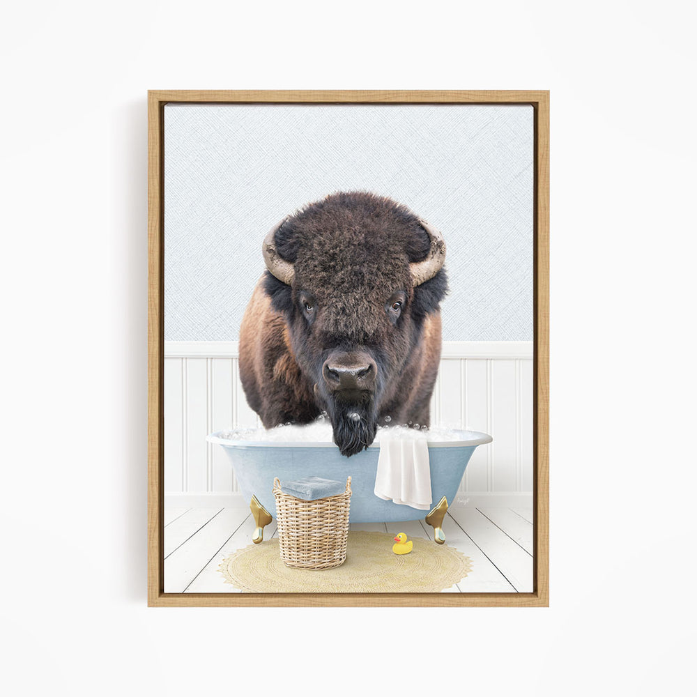 A buffalo with large horns is sitting in a blue bathtub filled with water, surrounded by rubber ducks.