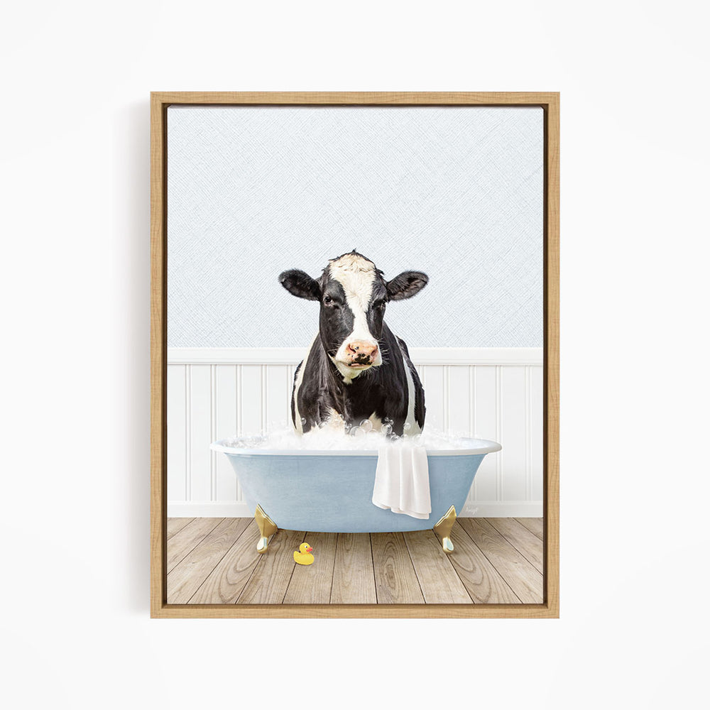A black and white cow is sitting in a blue bathtub filled with water, surrounded by rubber ducks.