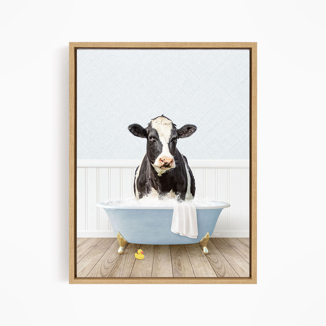 A black and white cow is sitting in a blue bathtub filled with water, surrounded by rubber ducks.