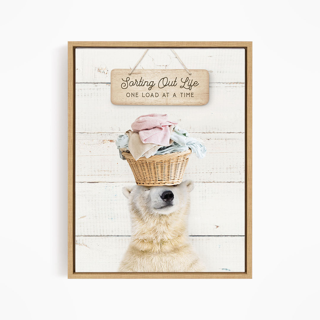 A polar bear balancing a basket of laundry on its head, with a sign above that says "Sorting Out Life One Load at a Time".