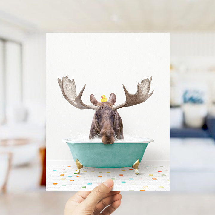 A moose with large antlers is sitting in a bathtub filled with bubbles, with a yellow rubber duck floating on its head.