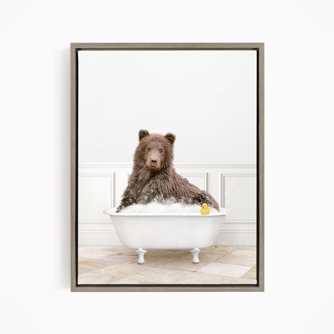 A brown bear sitting in a white bathtub, with a rubber duck floating in the water.