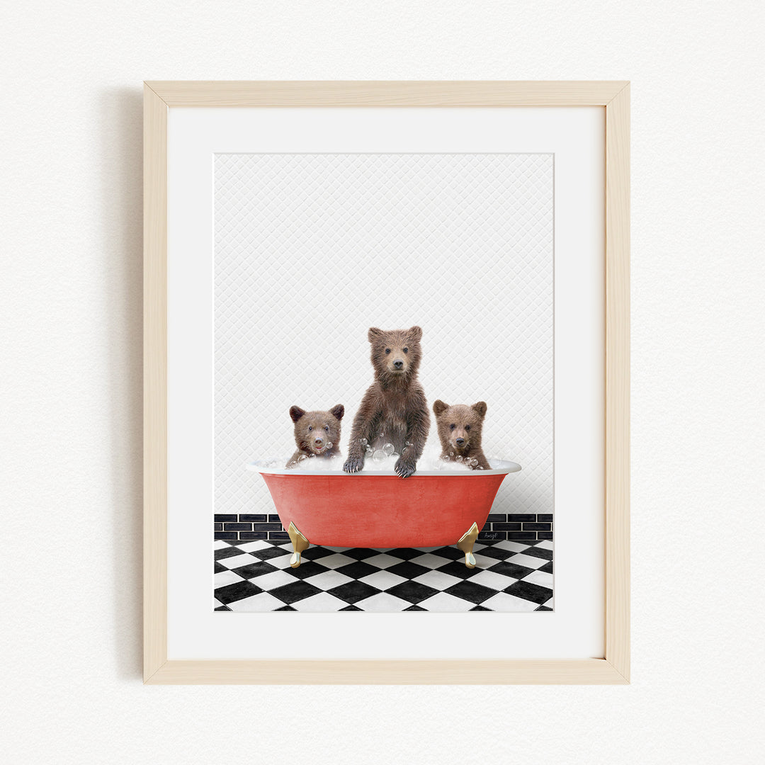 A framed image depicting three brown bears sitting in a red bathtub on a black and white checkered floor.