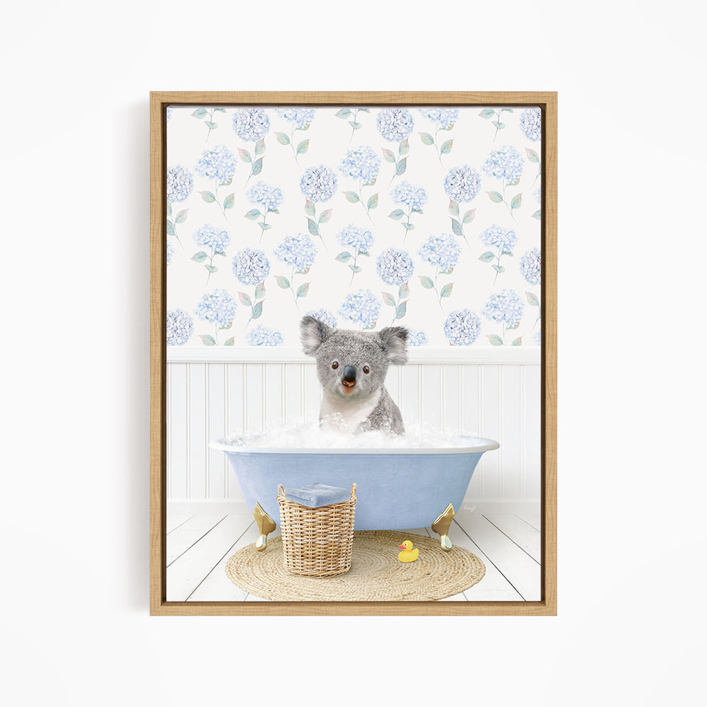 A koala bear sitting in a blue bathtub filled with water, surrounded by a wicker basket and rubber duckies.