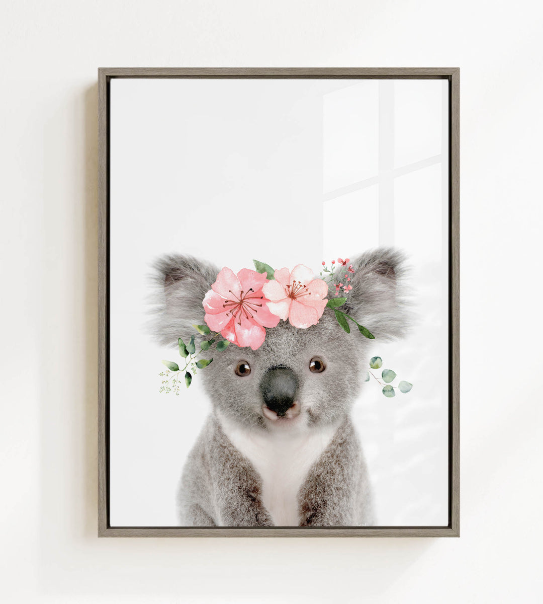 A cute koala bear wearing a floral crown on its head, with pink flowers and greenery surrounding it.