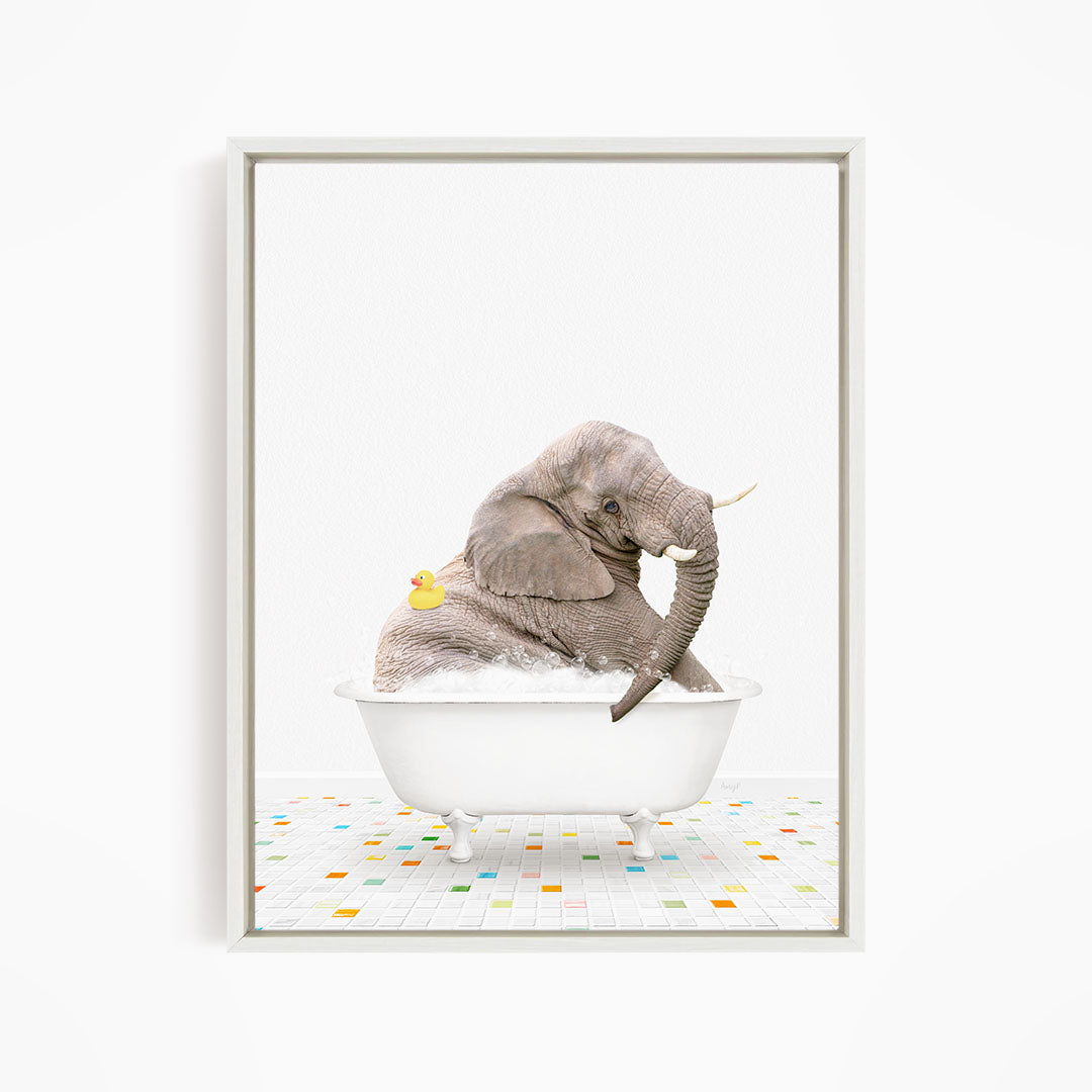 A gray elephant is sitting in a white bathtub, with a yellow rubber duck floating on the water.