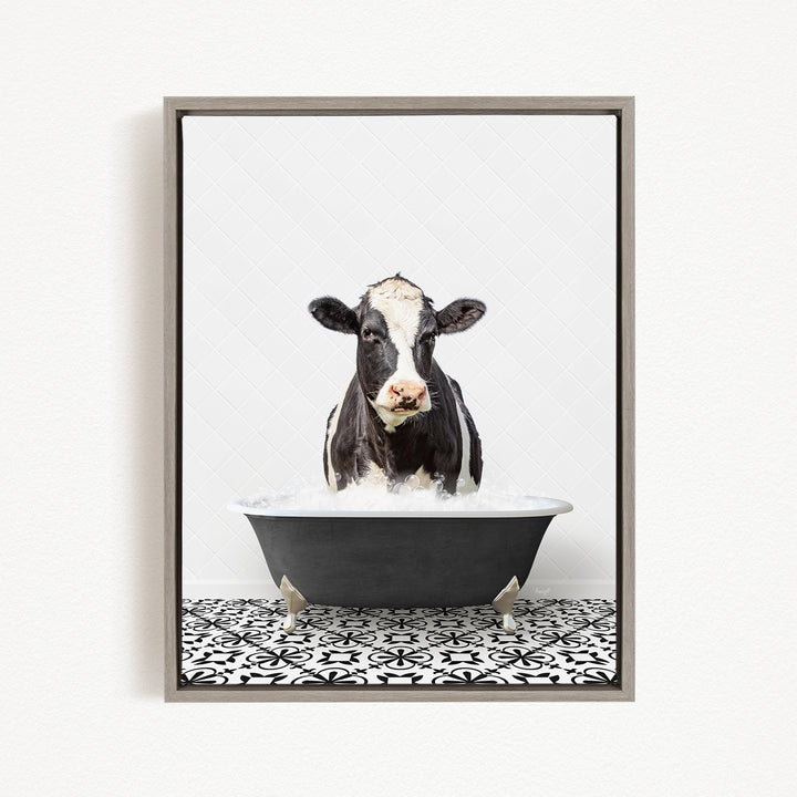 A black and white cow is sitting in a black bathtub filled with water, creating a whimsical and humorous scene.