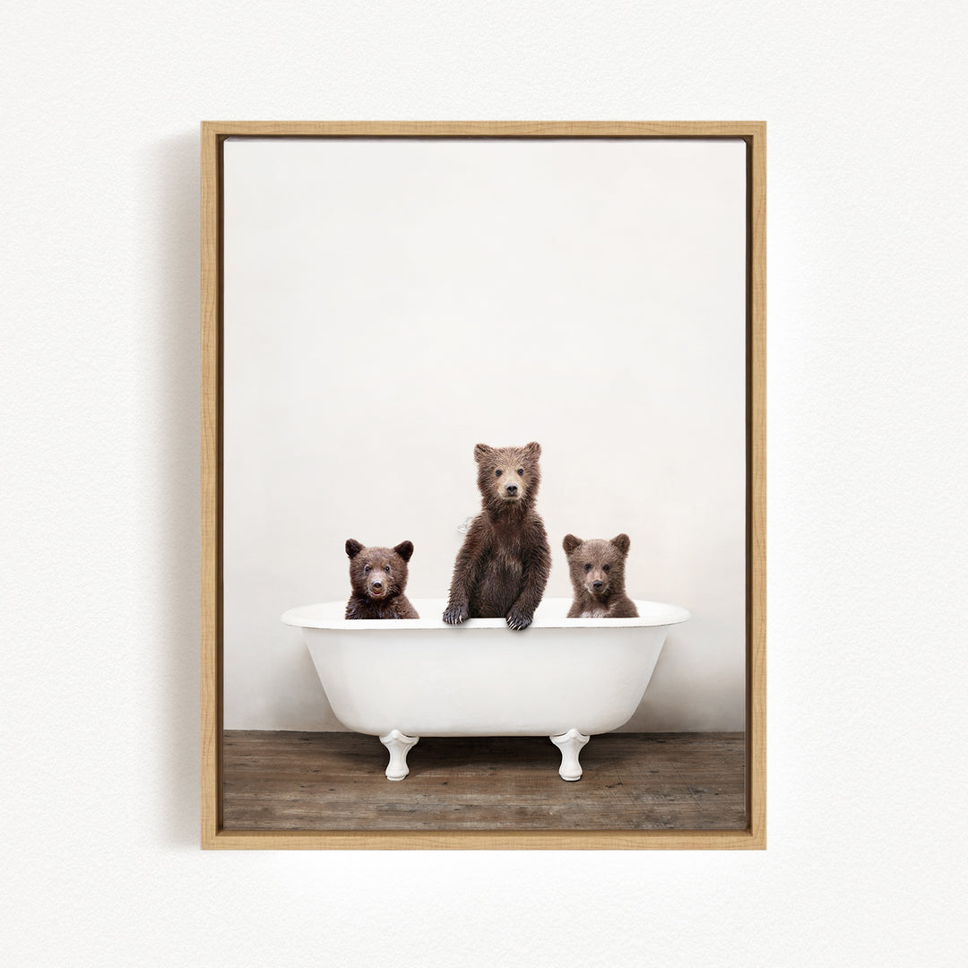 Three brown bears sitting in a white bathtub against a white background.