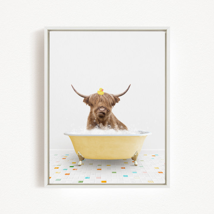 A brown cow with long horns is sitting in a yellow bathtub filled with bubbles, with a rubber duck perched on its head.