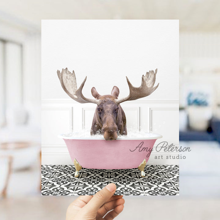 a person holding up a card with a moose head in a bathtub