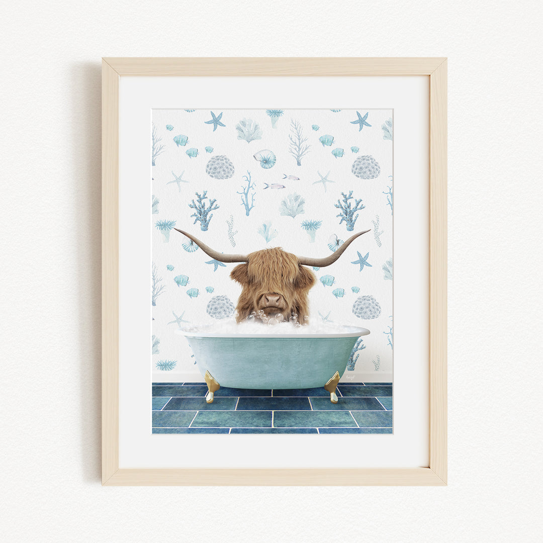A framed illustration depicting a Highland cow with long horns sitting in a bathtub filled with bubbles, surrounded by a blue and white ocean-themed wallpaper.