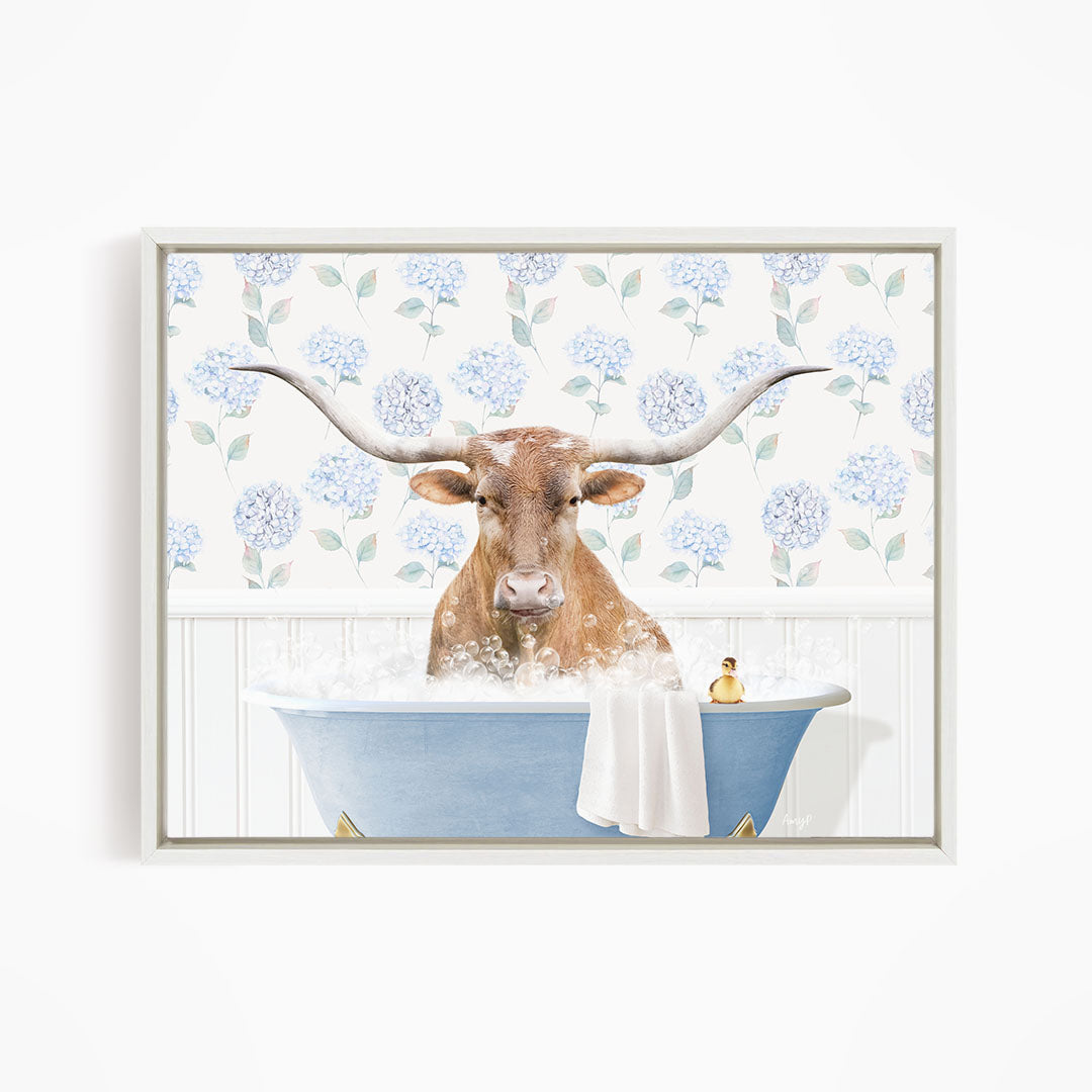 A brown cow with large horns is sitting in a blue bathtub filled with water, surrounded by a floral patterned wall.