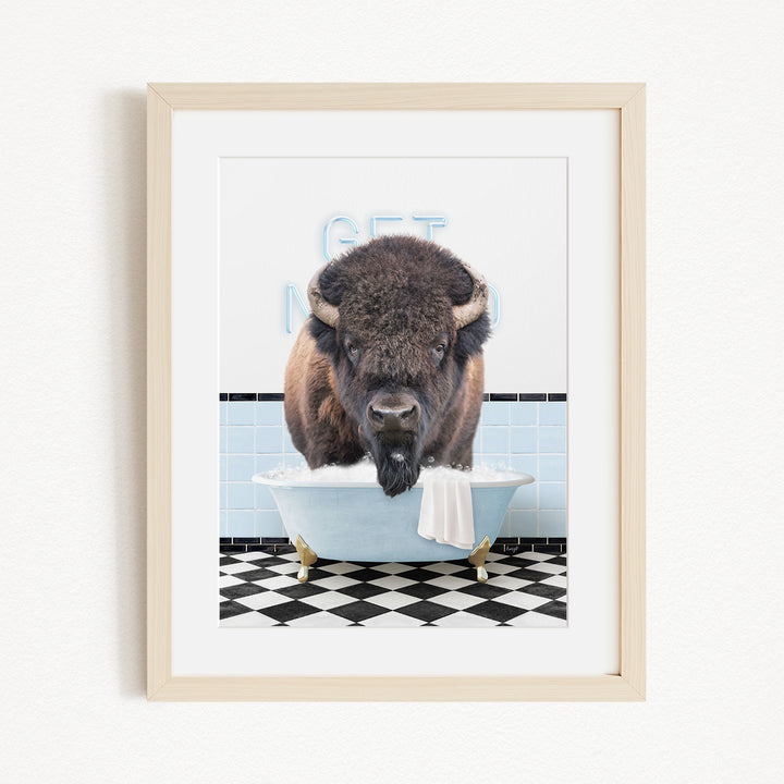 A buffalo standing in a bathtub filled with water, with a sign that says "GET IN THE WASH".