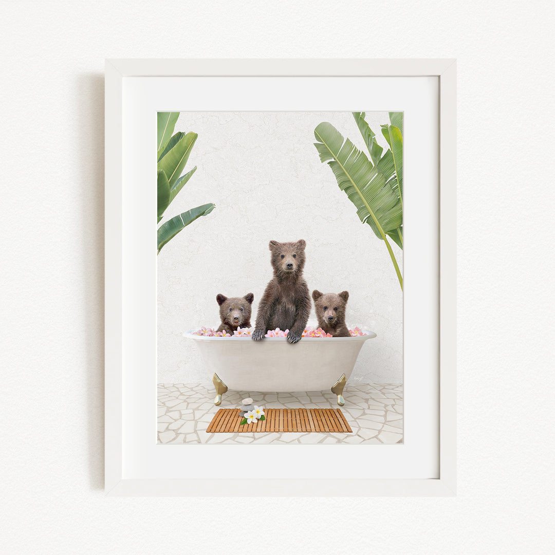 A framed image depicting three bears sitting in a bathtub filled with pink flowers, surrounded by green plants.