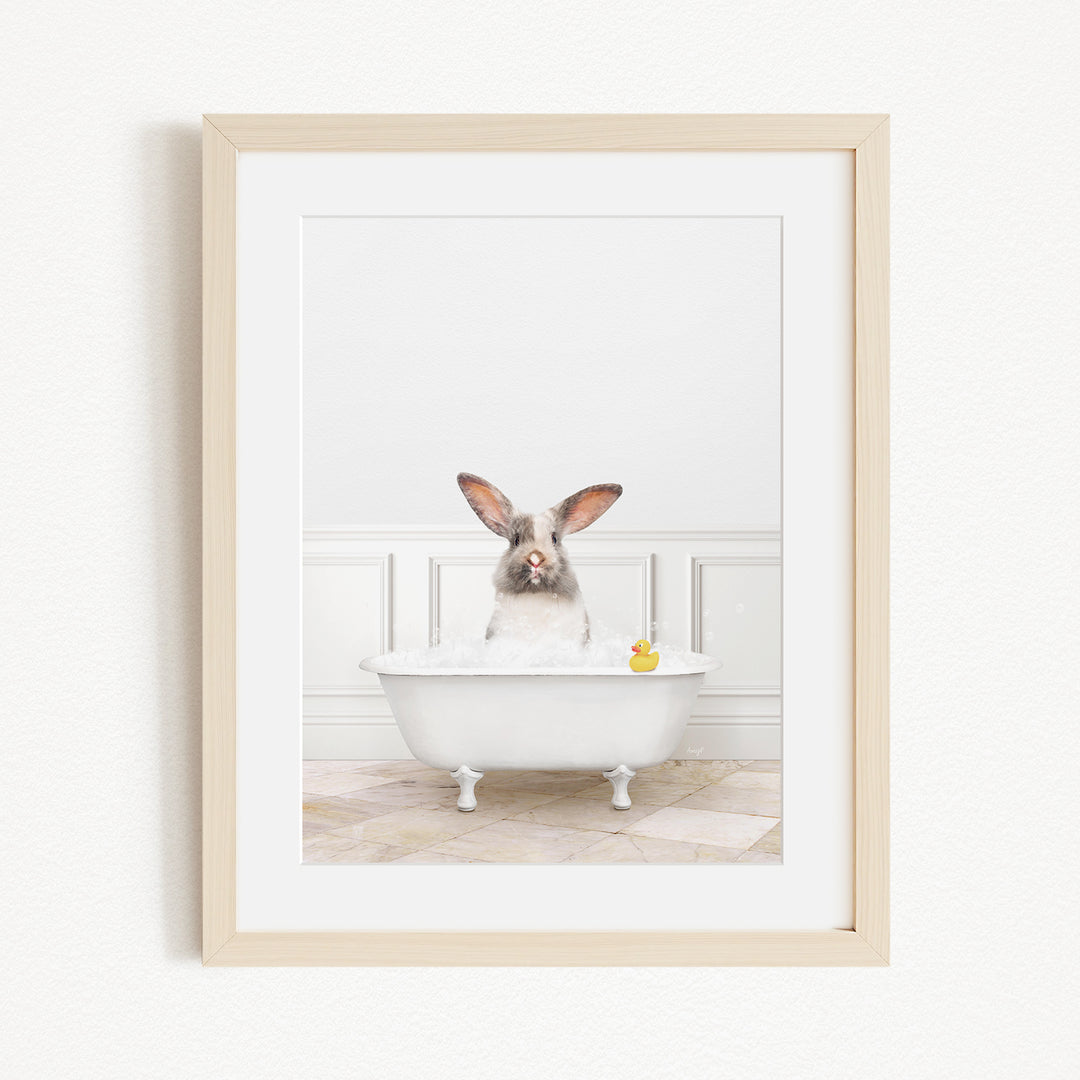 A white rabbit sitting in a white bathtub filled with bubbles, with a yellow rubber duck floating in the water.