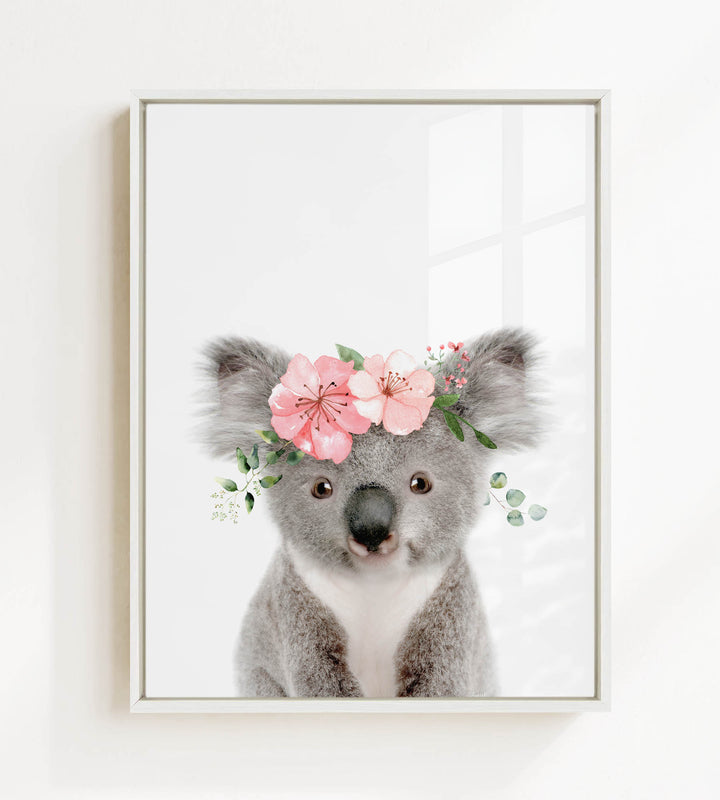 A cute koala bear wearing a floral crown on its head, with pink flowers and greenery surrounding it.