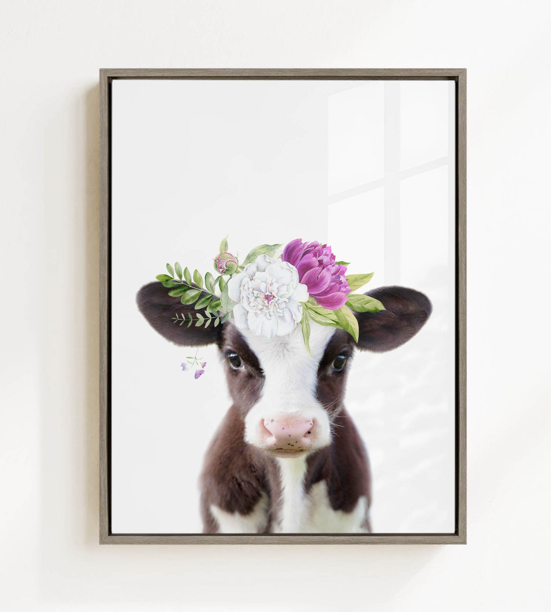 A framed print of a cow wearing a floral crown on its head.